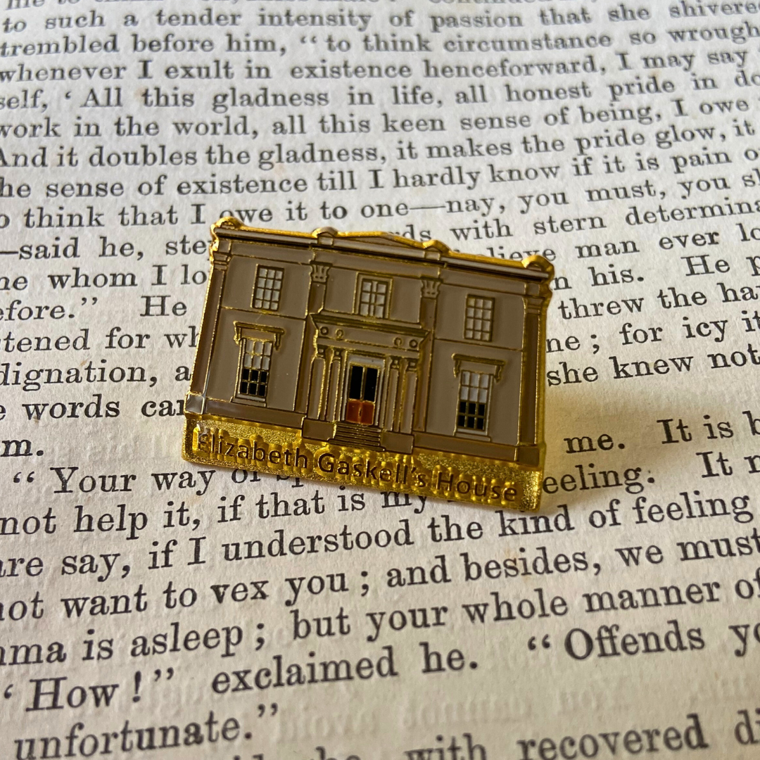 An Elizabeth Gaskell's House Pin Badge on a page of a book.